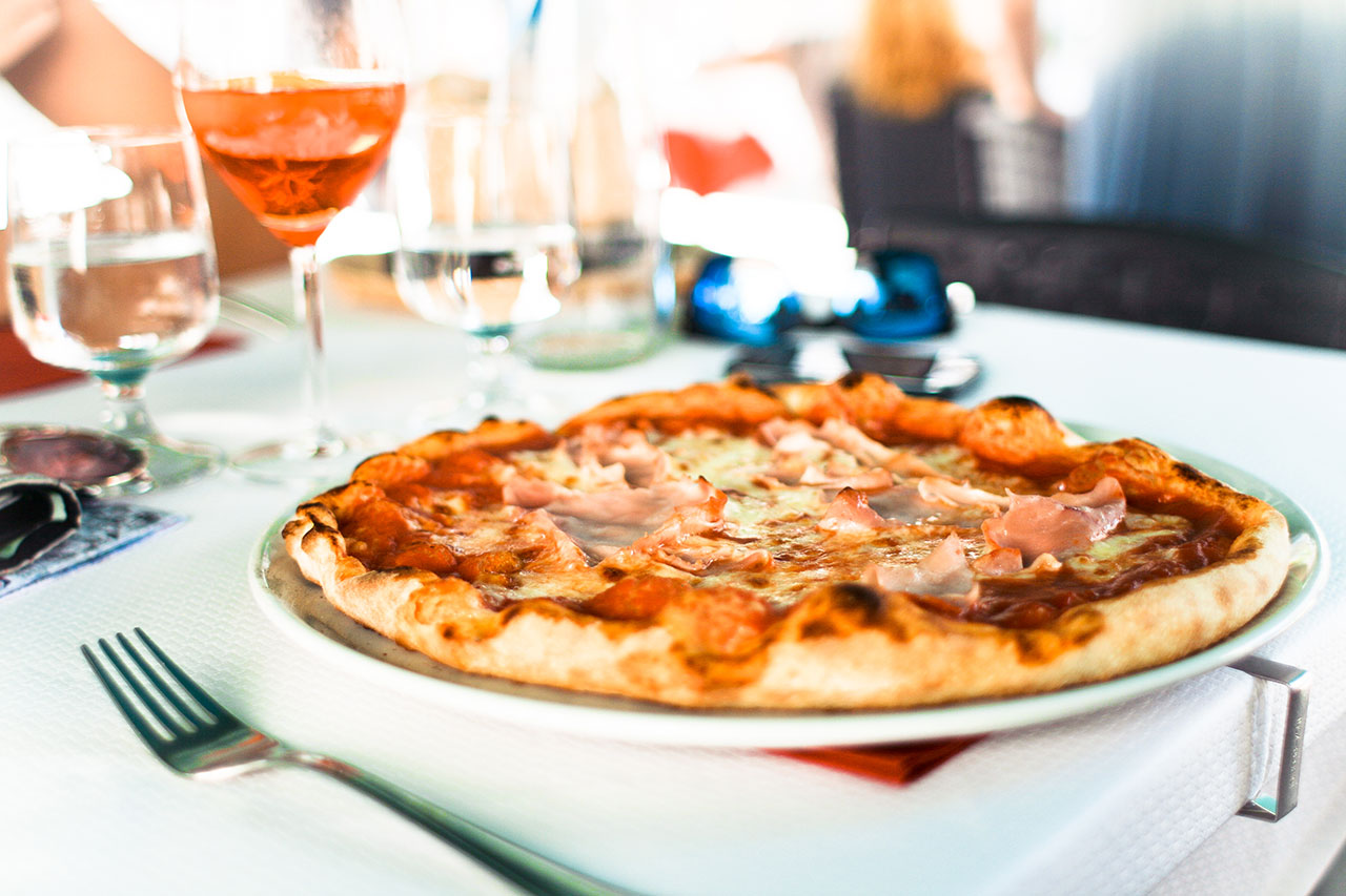 A pizza sitting on top of a pan near some wine glasses.