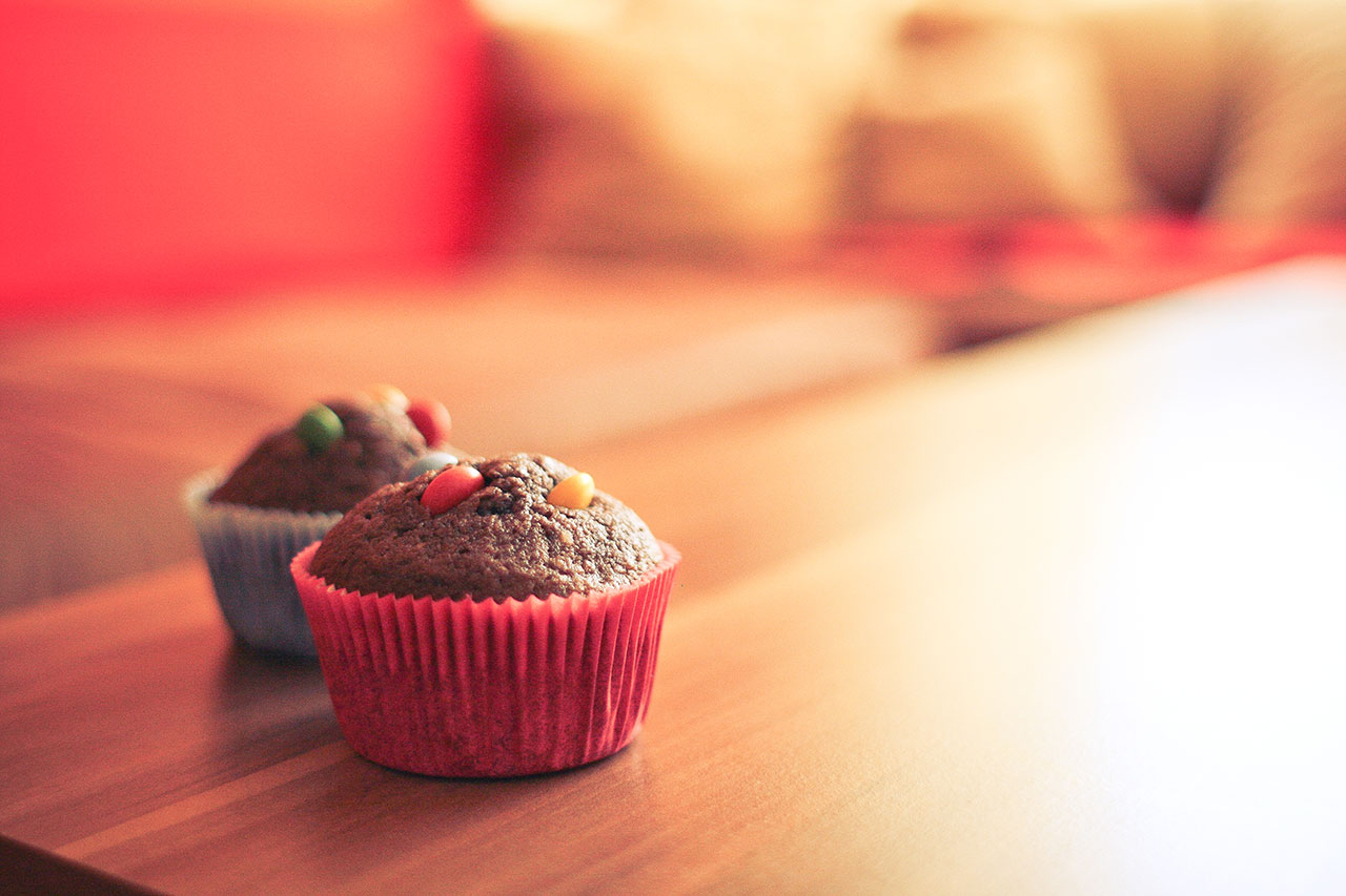 Two cupcakes sitting on a table with one in the foreground.
