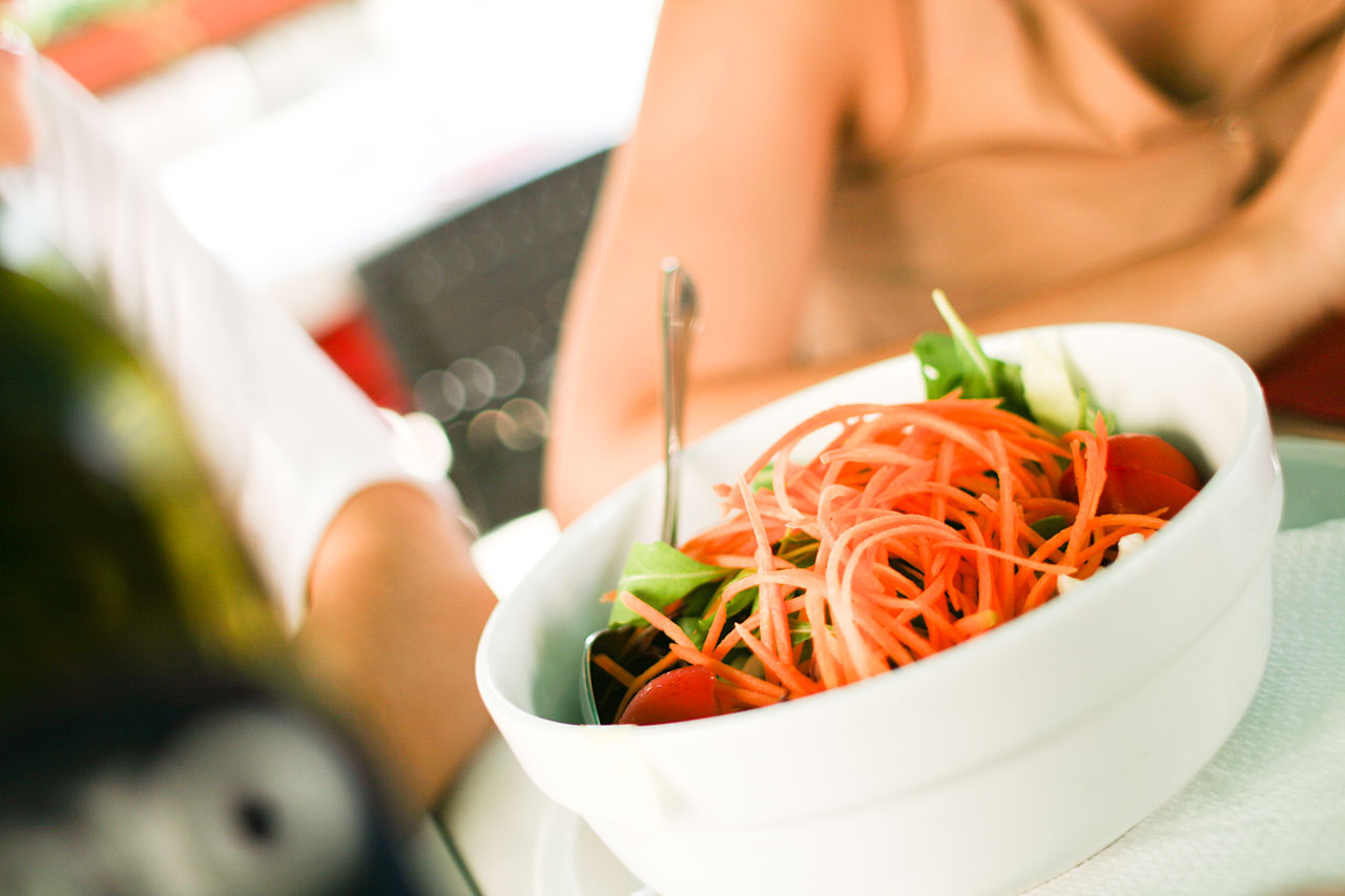 A bowl of salad with carrots and greens.