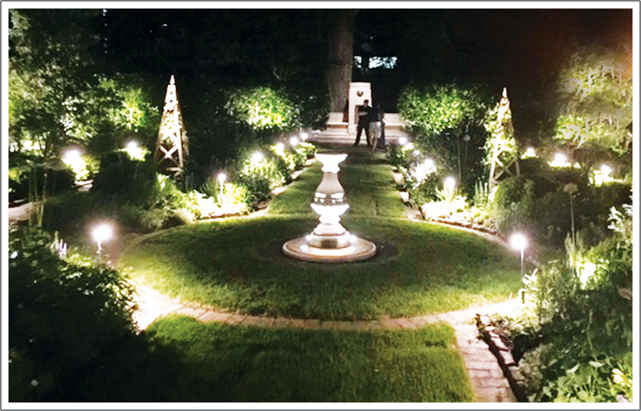 A garden with lights and fountains in the middle of it