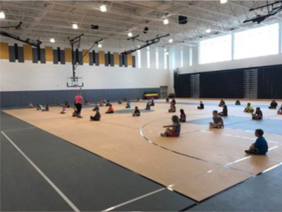 A gym with many people sitting on the floor