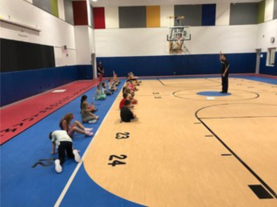 A group of people sitting on the floor in front of an instructor.