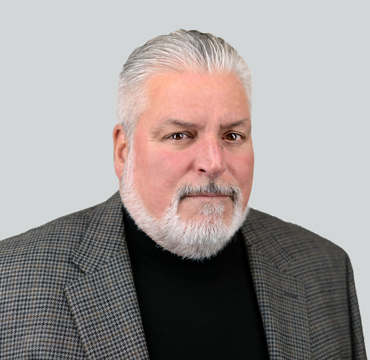 A man with white hair and beard wearing a black shirt.